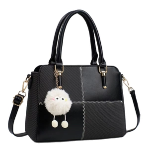 Chic black shoulder bag with textured panels, gold hardware and fluffy charm accessory