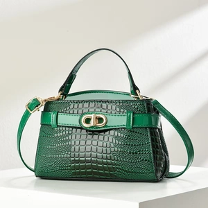 Close-up of dark green crocodile embossed handbag with a gold CD metal clasp