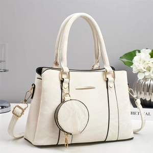 Detail view of cream handbag with gold hardware, adjustable strap and round coin purse