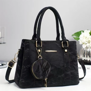 Detail of black textured handbag with gold hardware and mini round coin purse pendant