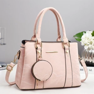 Detail of pink faux leather handbag with textured surface and round coin purse charm