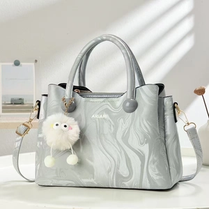 Detail of marble pattern handbag with AIGARI logo, plush charm, and golden zipper
