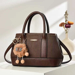 Detail of dark brown lychee leather handbag with vertical texture and plush ball charm