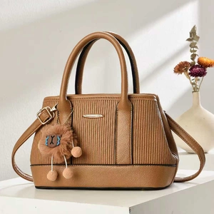 Brown textured leather handbag with plush charm on a minimalist display stand