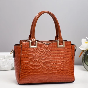 Detail of caramel crocodile pattern handbag with gold hardware and circular handles