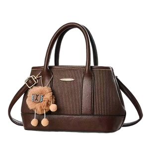 Coffee brown textured leather handbag with vertical stripes and fuzzy pom-pom charm