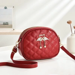 Detail of red quilted PU leather crossbody bag with gold flamingo charm and dual zippers