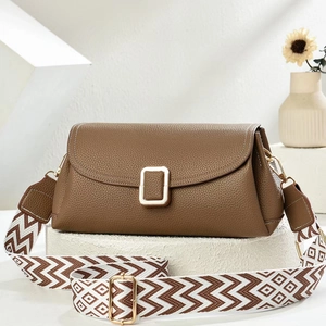 Close-up of brown litchi leather bag with gold buckle and textured geometric woven strap