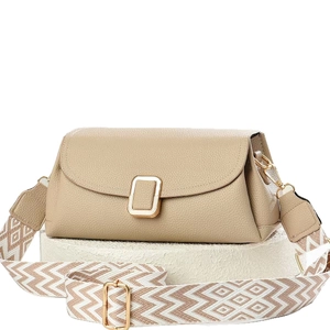 Beige textured leather crossbody bag with geometric woven strap on a white stone pedestal