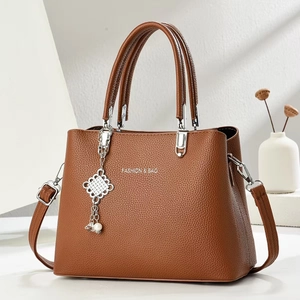 Brown lychee leather crossbody bag with top handles and pearl knot pendant
