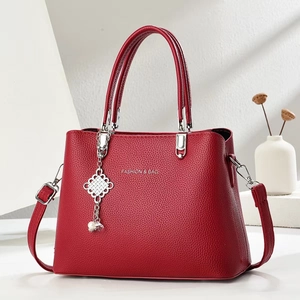 Detail of red pebbled leather tote bag with silver hardware and pearl charm decoration