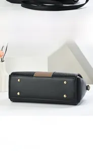Dettaglio del fondo della borsa nera con piedini in metallo dorato e pelle martellata