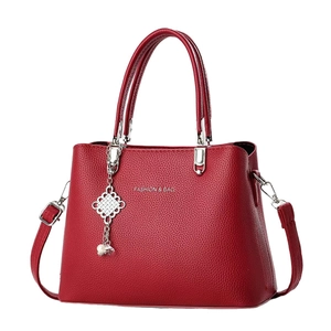Deep red lychee grain leather handbag with silver hardware and tassel charm detail
