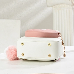 Detail of the bottom metal feet and cute pink plush ball charm on the PU leather bag