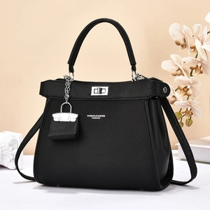 Sac cabas noir bicolore avec détails argentés et bandoulière sur un bureau minimaliste