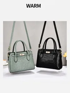 Detail van de krokodillentextuur en gouden draaisluiting op de tote handtas voor dames