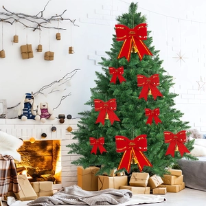 Red sequined Christmas bows with gold bells hanging on a green tree branch