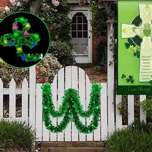 St. Patrick's Day green tinsel garland with colorful LED lights on white garden fence