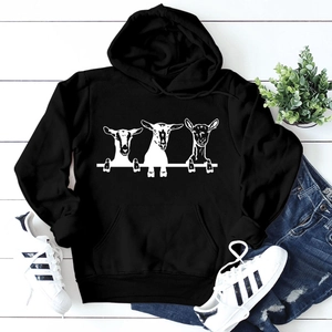 Detail of black hoodie with white goat print, kangaroo pocket and drawstring on wood