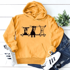 Close-up of yellow hoodie with goat print paired with jeans on white wooden background