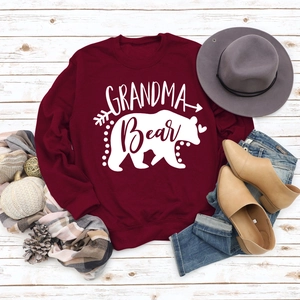 Flat lay of Grandma Bear sweatshirt with autumn accessories on white wooden floor