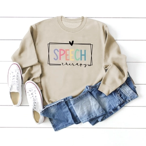 Close-up of khaki crewneck sweatshirt with Speech Therapy lettering on wooden background