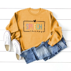 Flat lay detail of mustard yellow sweatshirt with Speech Therapy print and denim styling