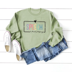 Flat lay of green Speech Therapy sweatshirt with denim shorts and white sneakers