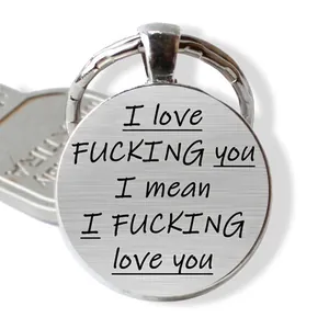 Close-up of a silver round keychain pendant with bold humorous text and metal ring