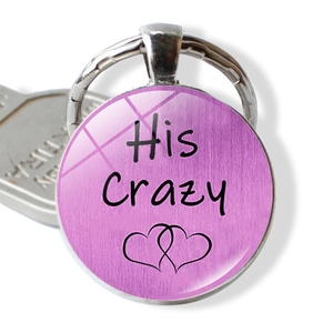 Detail of round keychain with His Crazy lettering and interlocking hearts over purple base