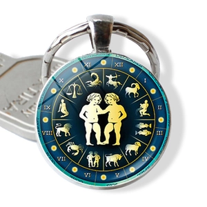 Macro shot of Gemini zodiac glass dome keychain with golden astrological map and months