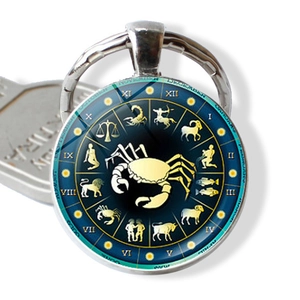 Detailed macro view of Scorpio zodiac glass cabochon pendant on a vintage silver keychain