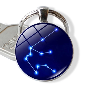 Macro detail of Aquarius zodiac glass pendant with silver keychain and starry galaxy background