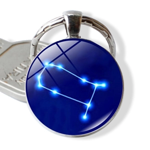 Macro detail of Gemini constellation glass dome keychain with luminous star map pattern