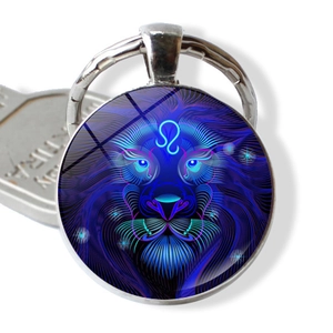 Detailaufnahme eines Neon-Löwe-Sternzeichens unter Glas-Cabochon auf einem silbernen Schlüsselbund