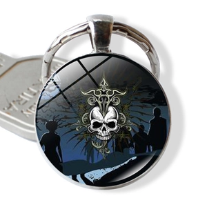 Detailed macro view of a Gothic skull keychain pendant with silver metal ring and blue background