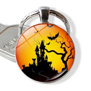 Halloween keychain with a round glass dome featuring a castle, bats, and sunset scenery