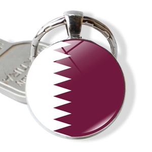 Detail of round metal keychain featuring the Qatar national flag under a glass dome charm