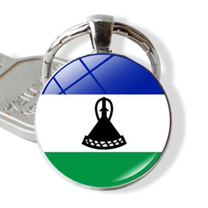 Detail of Lesotho flag keychain with a glass cabochon pendant next to a silver key