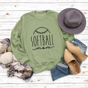 Détail du sweat vert sauge avec imprimé Softball Mom et finitions côtelées sur bois blanc