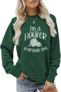 Detail of white text and crochet hook graphic on a dark green long sleeve sweatshirt
