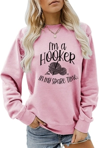 Close-up of pink crewneck sweatshirt with 'I'm a HOOKER' slogan and crochet graphics