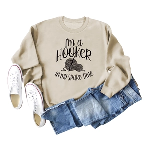 Detail view of beige sweatshirt featuring humorous crochet theme text and yarn ball graphic