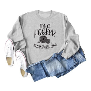Flat lay of gray sweatshirt with humorous crochet print and blue denim skirt