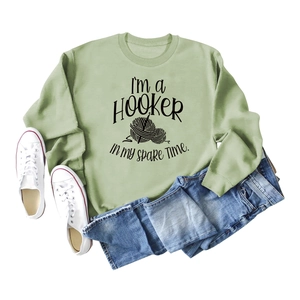 Detailed flat lay of a sage green sweatshirt with a crochet hobby slogan and soft fabric