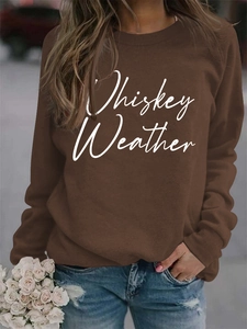 Close-up of white Whiskey Weather text on a brown long-sleeved autumn sweatshirt