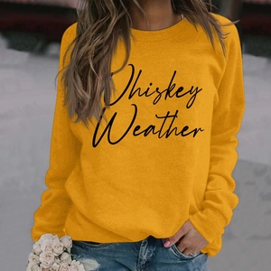 Close-up of mustard yellow sweatshirt featuring Whiskey Weather cursive print design