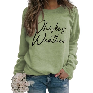 Detail of sage green sweatshirt with Whiskey Weather slogan print on model with flowers