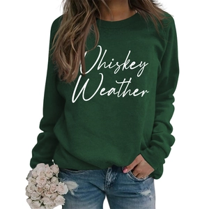 Close-up of Whiskey Weather printed text on dark green long sleeve crewneck sweatshirt