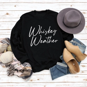 Flat lay of black Whiskey Weather sweatshirt with autumn accessories on white wood